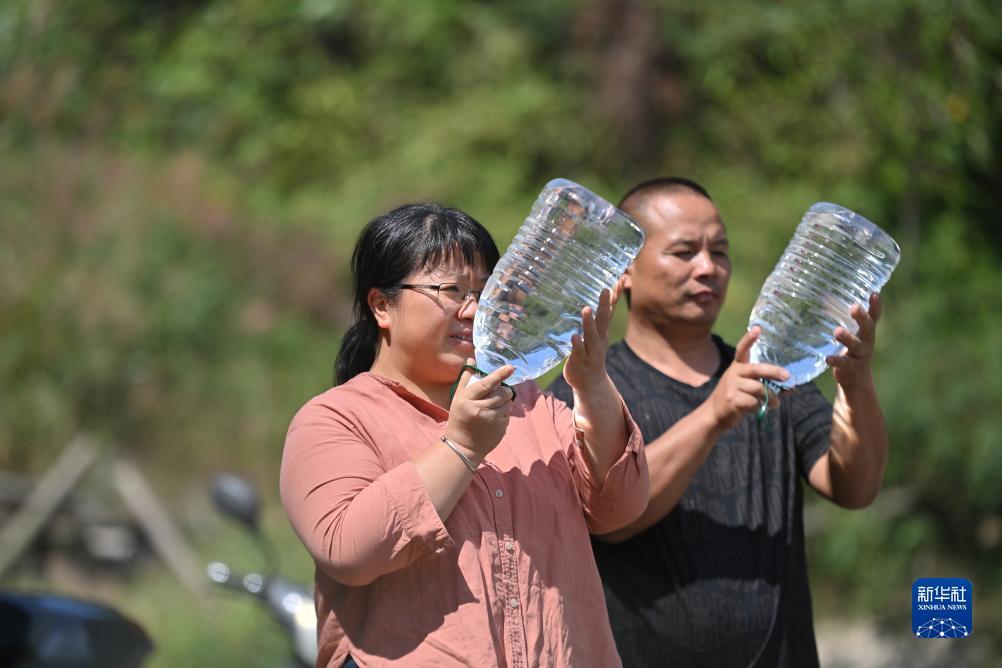 楊寧（左）在查看村民剛剛采集的水樣，為山泉水引水工程做準(zhǔn)備（10月8日攝）。新華社記者 黃孝邦 攝